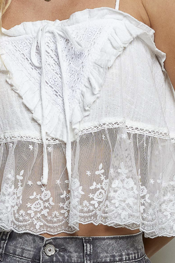 Woman wearing white babydoll cami on plain background