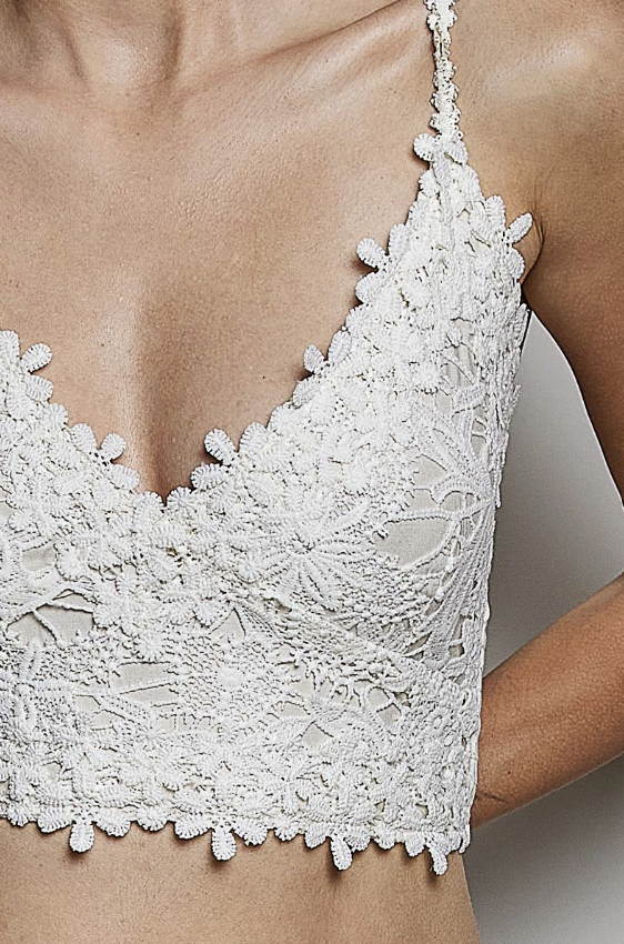 White lace bralette with floral lace pattern and scalloped edges, shown on a model.