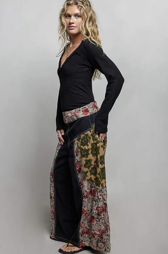 Woman wearing a black top and floral skirt against a plain background