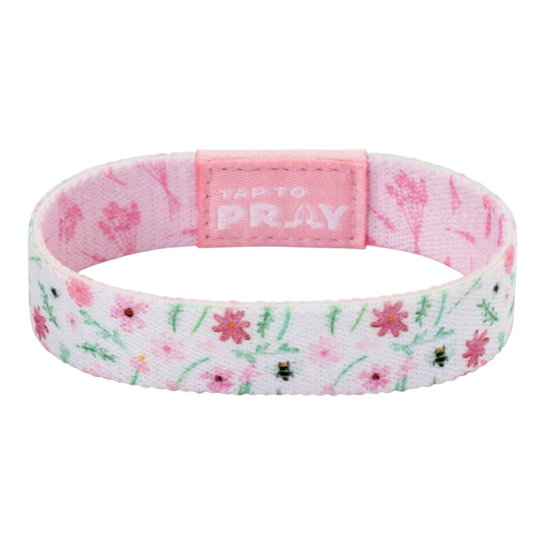A pink fabric wristband with a floral pattern, featuring a central pink tab with the text &