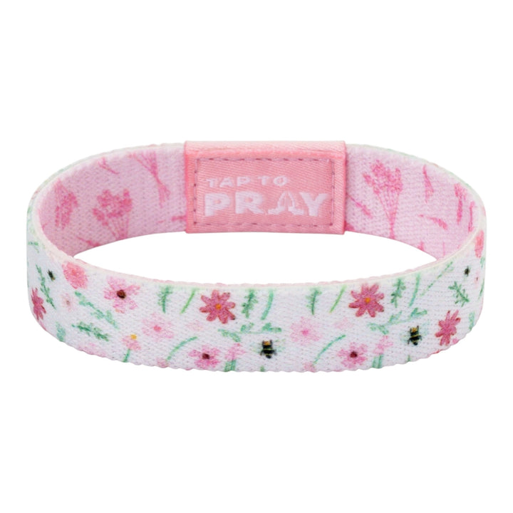A pink fabric wristband with a floral pattern, featuring a central pink tab with the text &