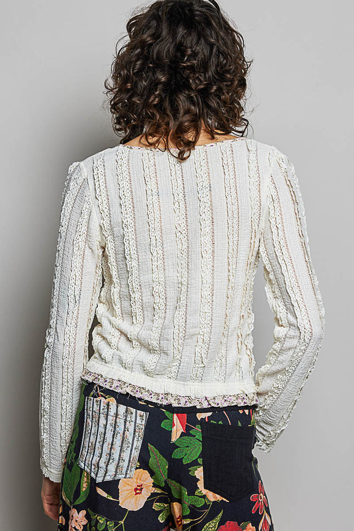 Person wearing a textured white top with floral pants on a gray background