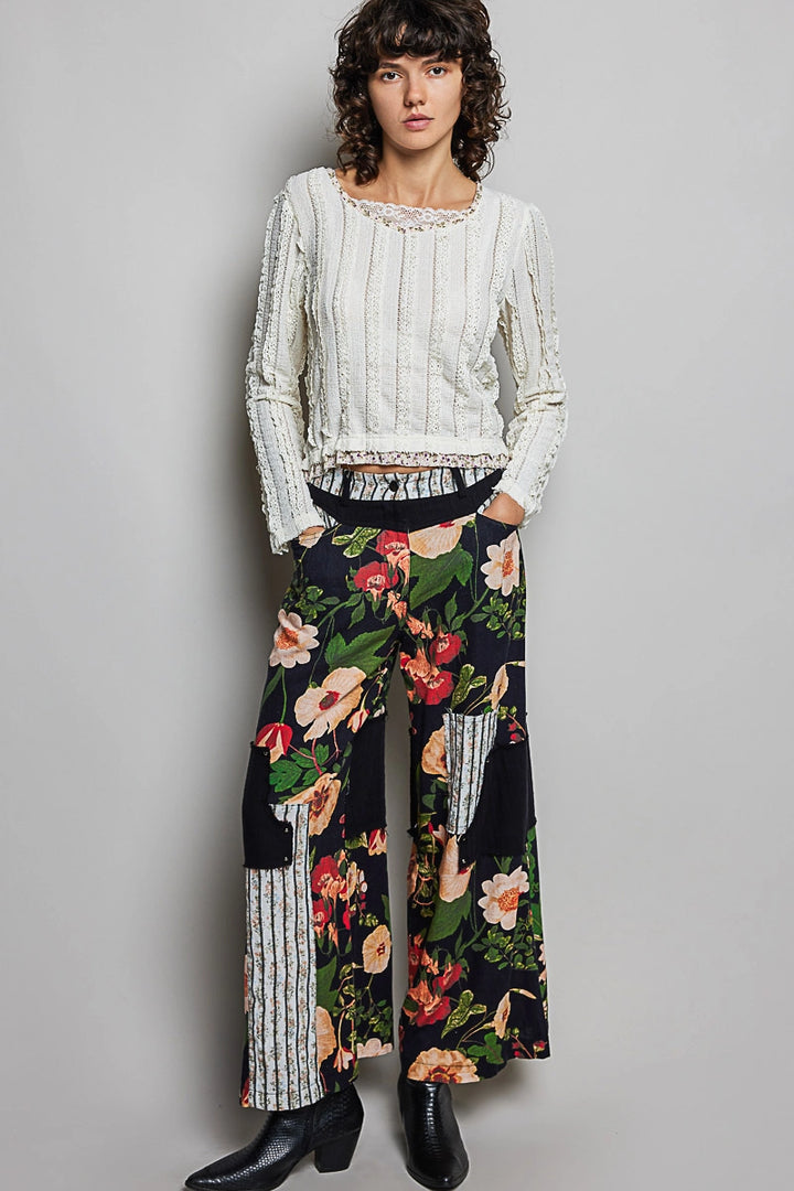 Woman wearing a white top and floral pants against a gray background