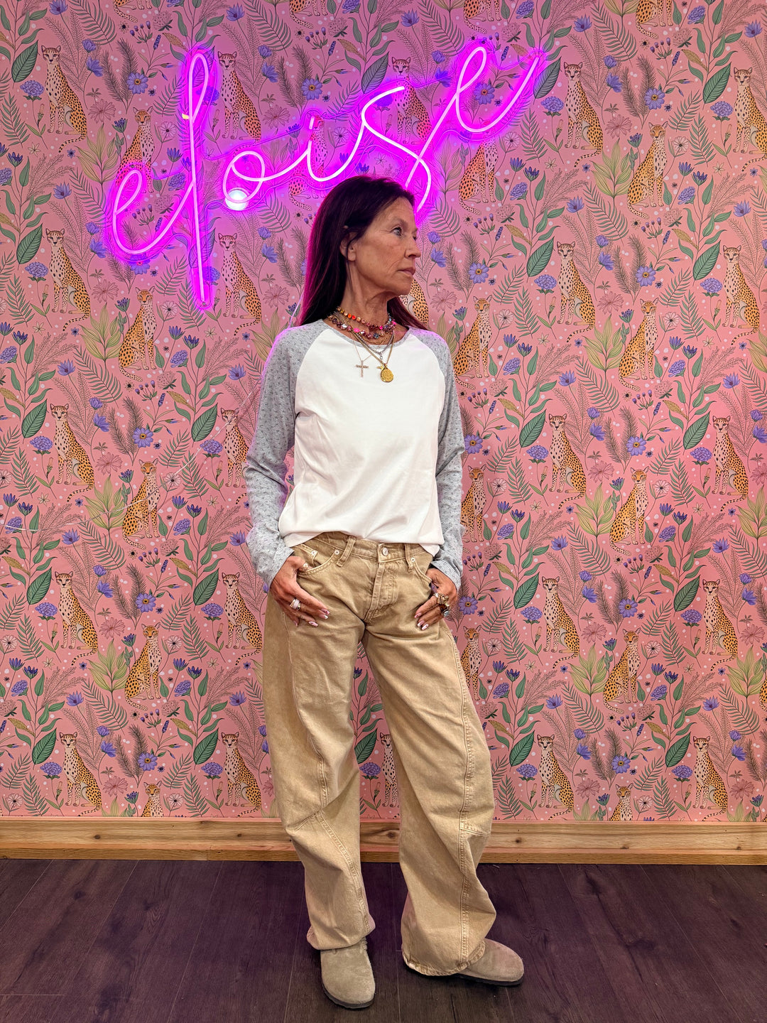 Woman wearing white and grey raglan tee with floral print on sleeves on floral background