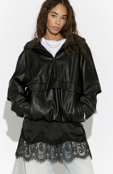 Person wearing a black leather jacket with lace trim on a white background