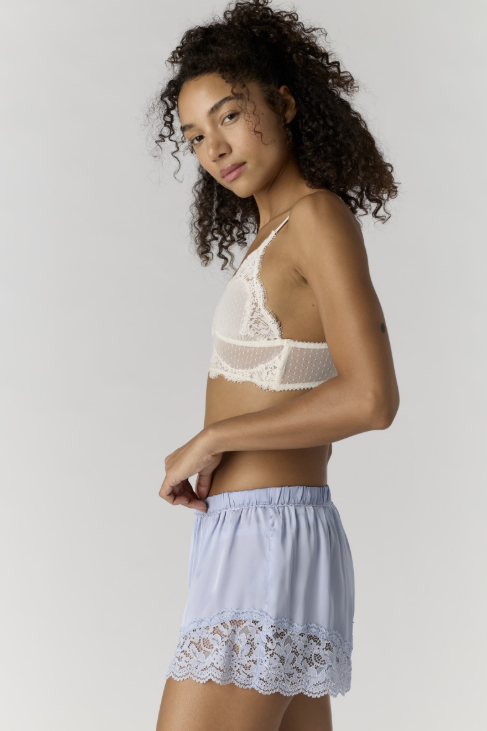 Woman wearing a lace bra and shorts set on a plain background
