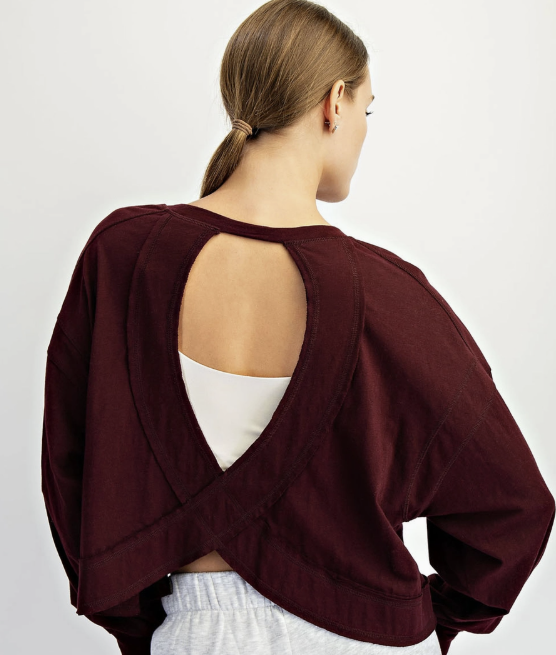Woman shown from back wearing open back burgundy top on white background