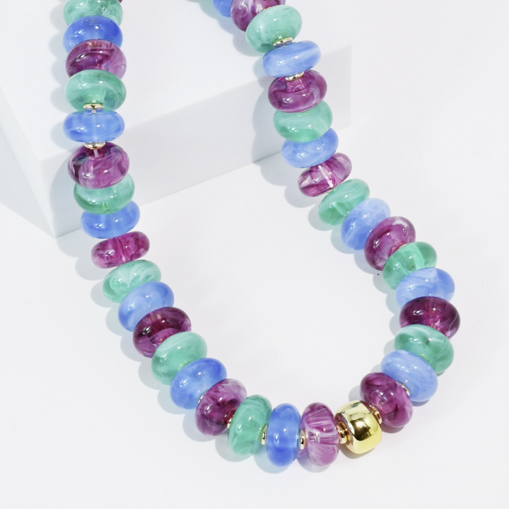 Chunky beaded necklace with purple, blue and teal beads on white background
