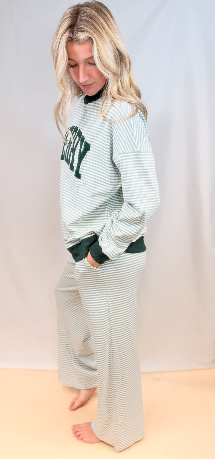 Woman shown from side view wearing matching sage and ivory stripe set on plain background