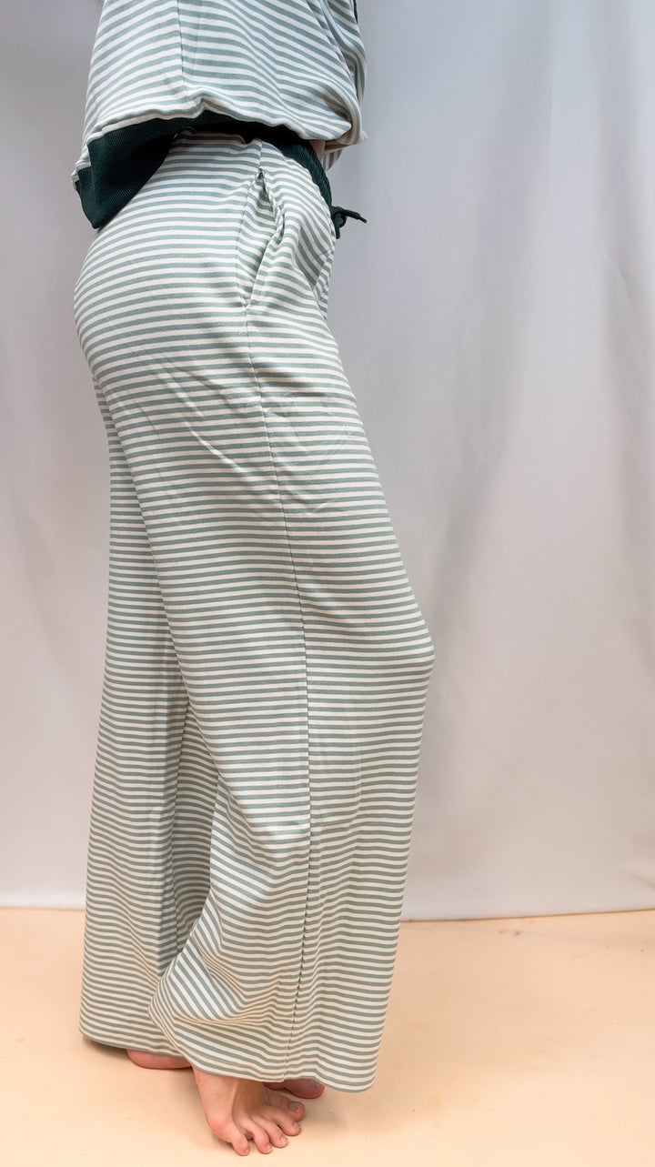 Woman shown from side view, waist down wearing sage and ivory stripe set on plain background