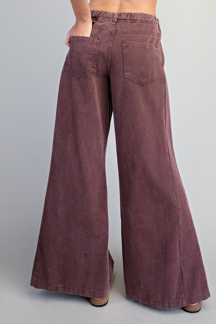 Wide-leg corduroy pants in a dusty mauve-brown color, shown from the back on a model against a light gray studio background.