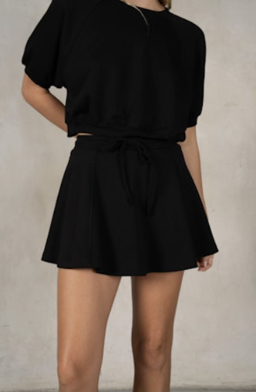 Person wearing a black romper against a plain background