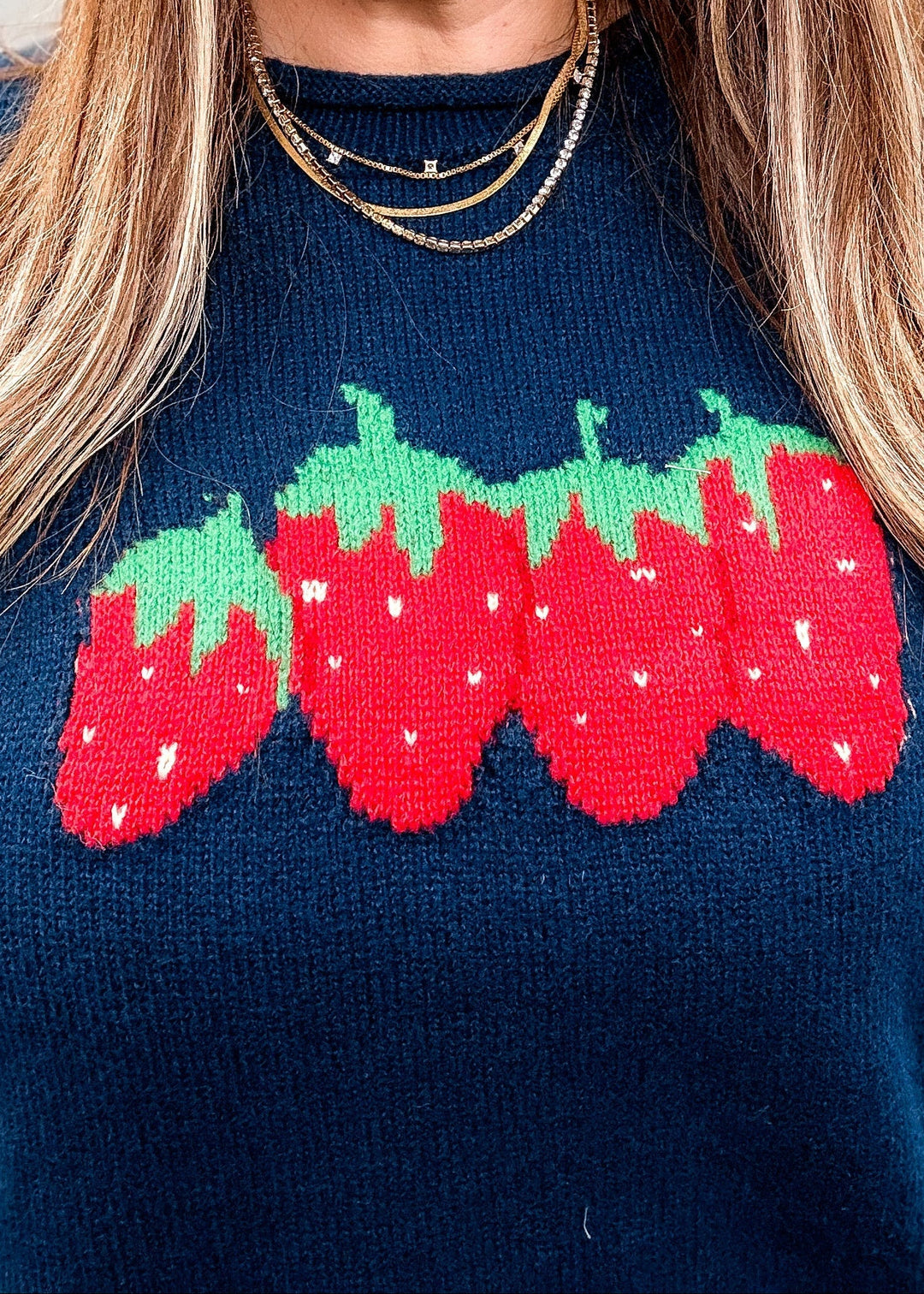 Close up of woman wearing navy blue sweater with strawberry design