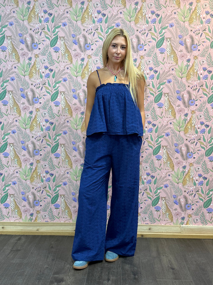 Woman wearing a blue outfit standing against a patterned wall.