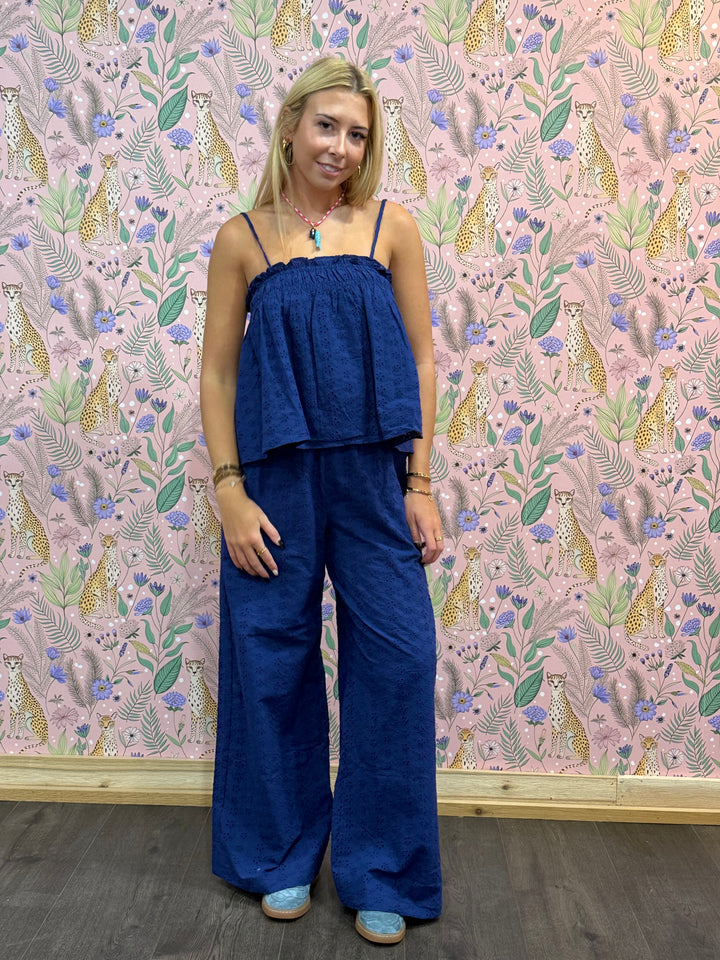 Woman wearing a blue jumpsuit standing in front of a patterned wall.