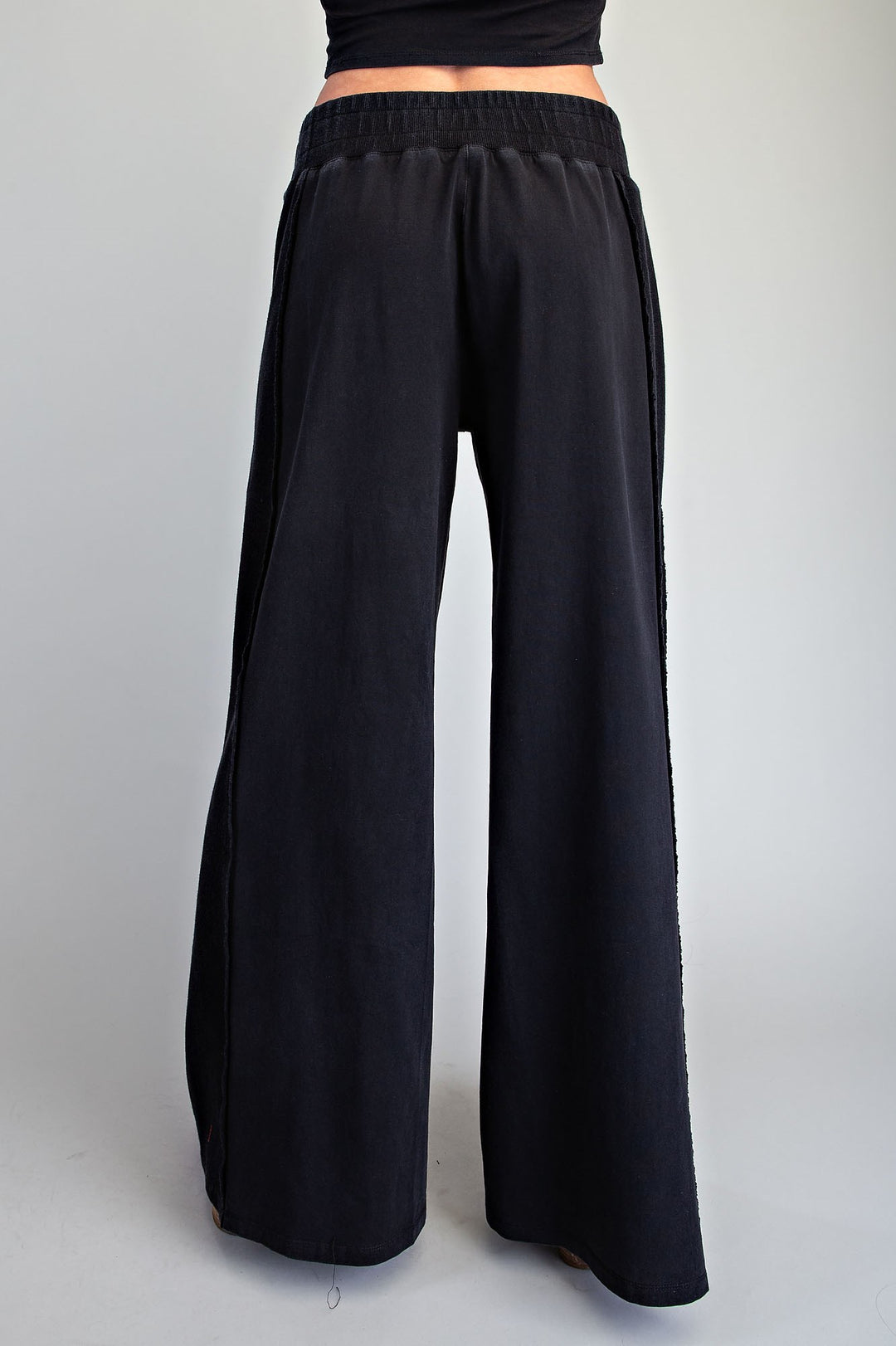 Black wide-leg pants with an elastic waistband, shown from the back on a model against a light gray background.