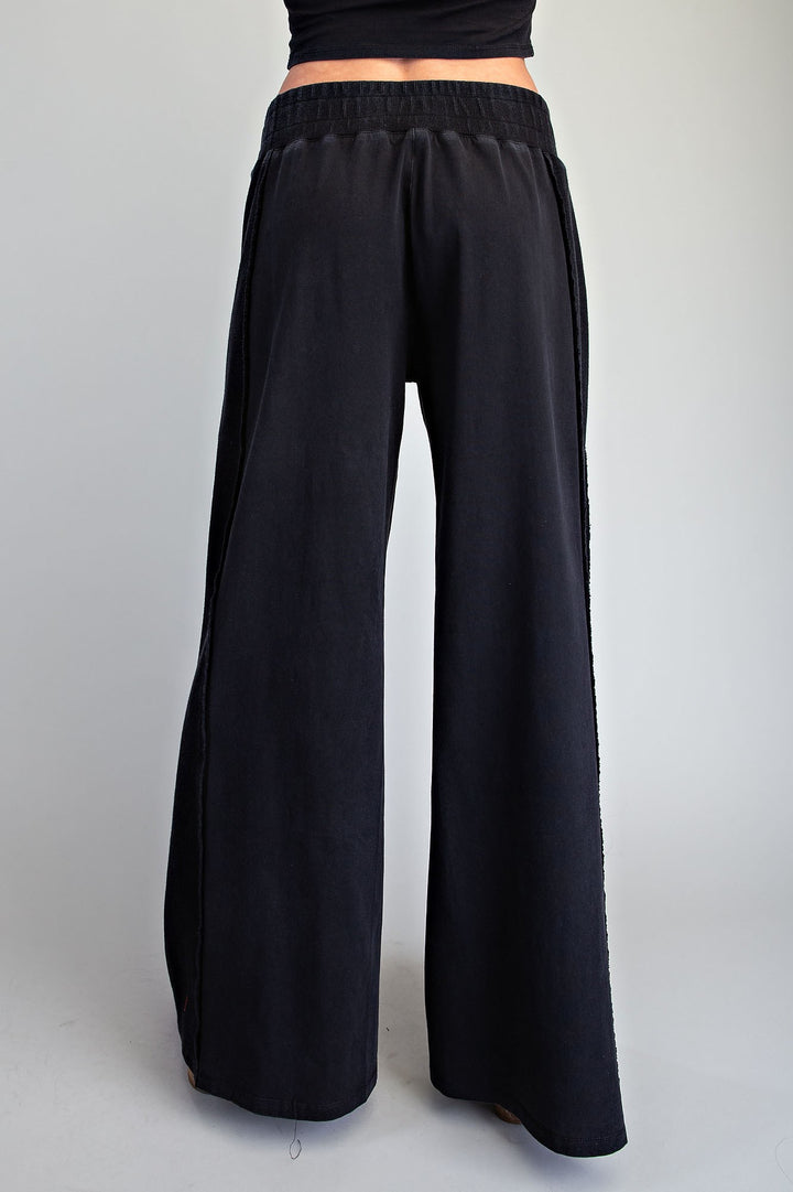 Black wide-leg pants with an elastic waistband, shown from the back on a model against a light gray background.
