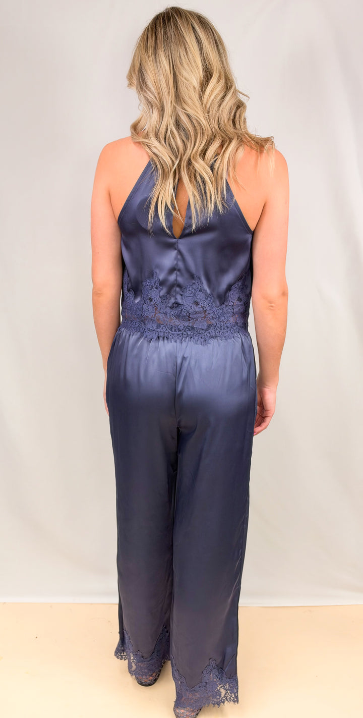 Woman shown from back wearing blue satin matching set on plain background