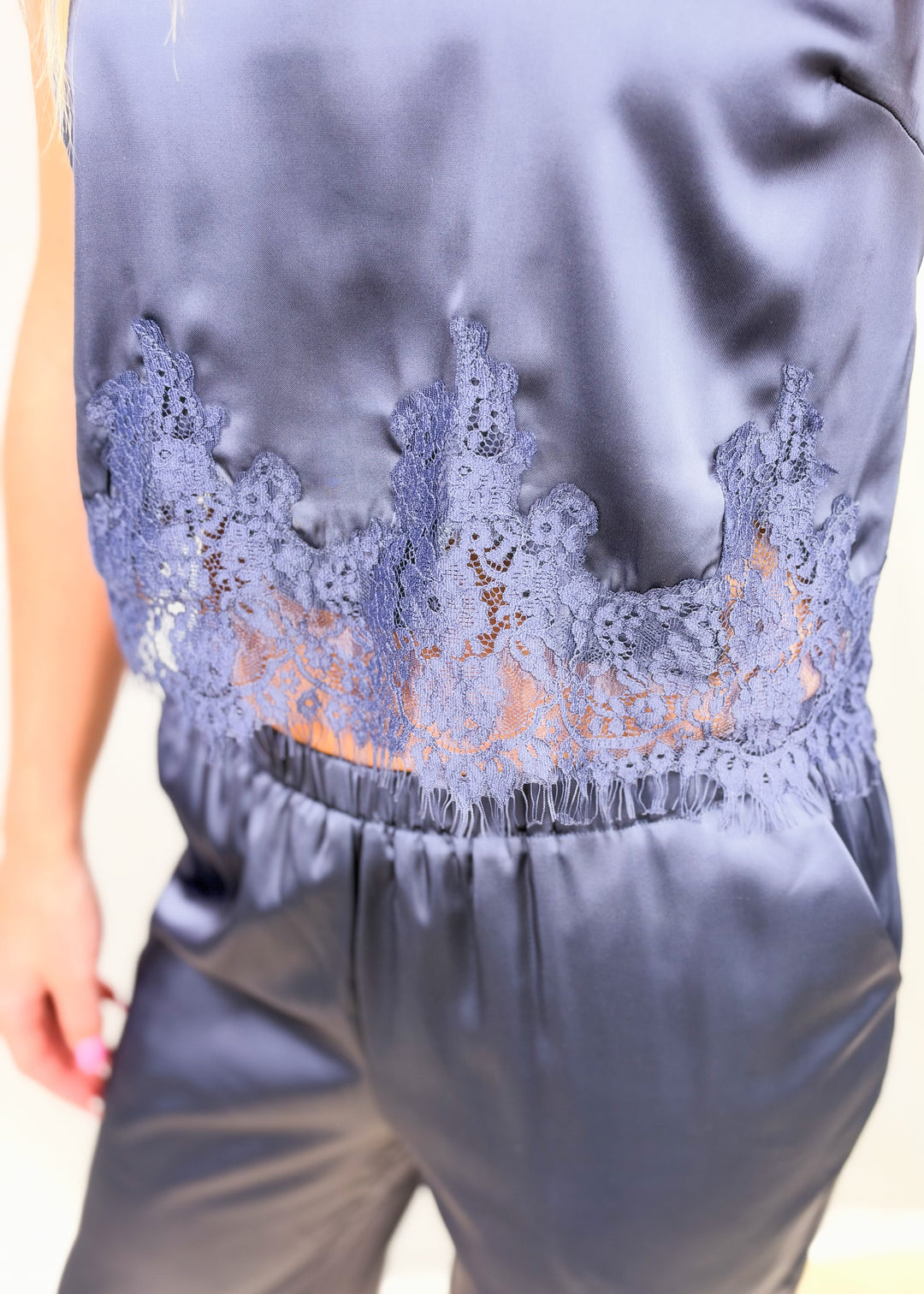 Close up detail show of blue satin set with lace detail on plain background