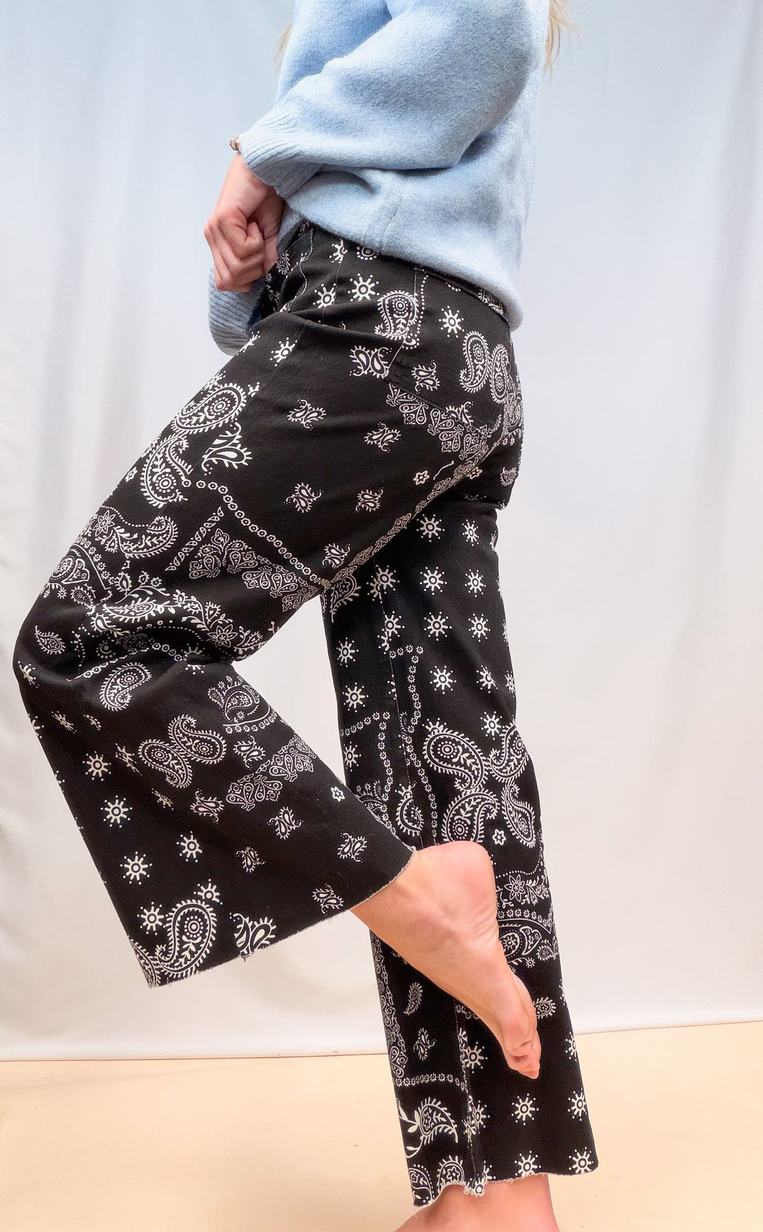 Woman shown from side view wearing black bandana pants on plain background