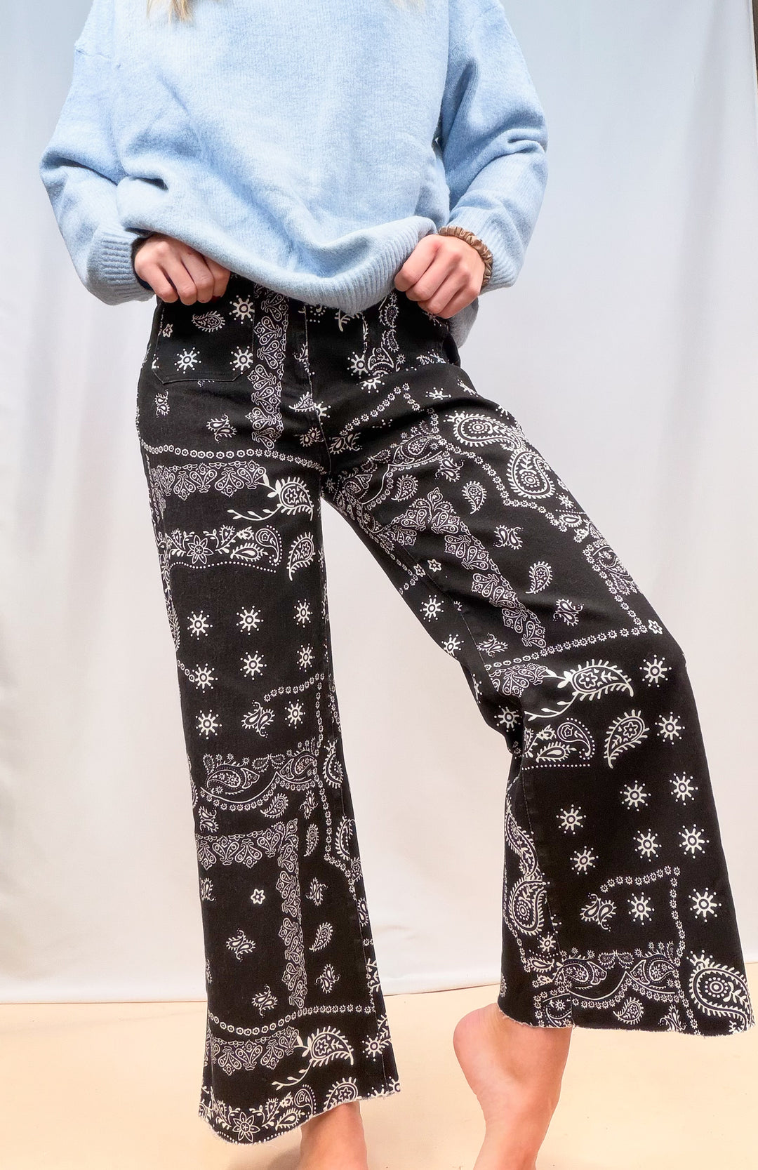 Woman shown from waist down wearing black bandana pants on plain background