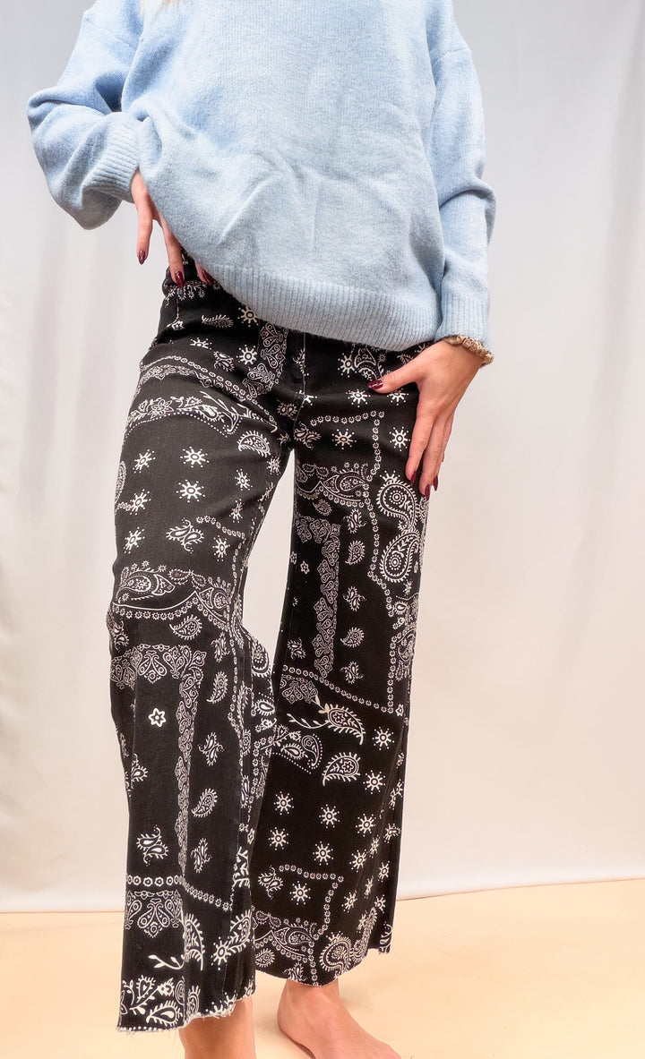 Woman shown from waist down wearing black bandana pants on plain background