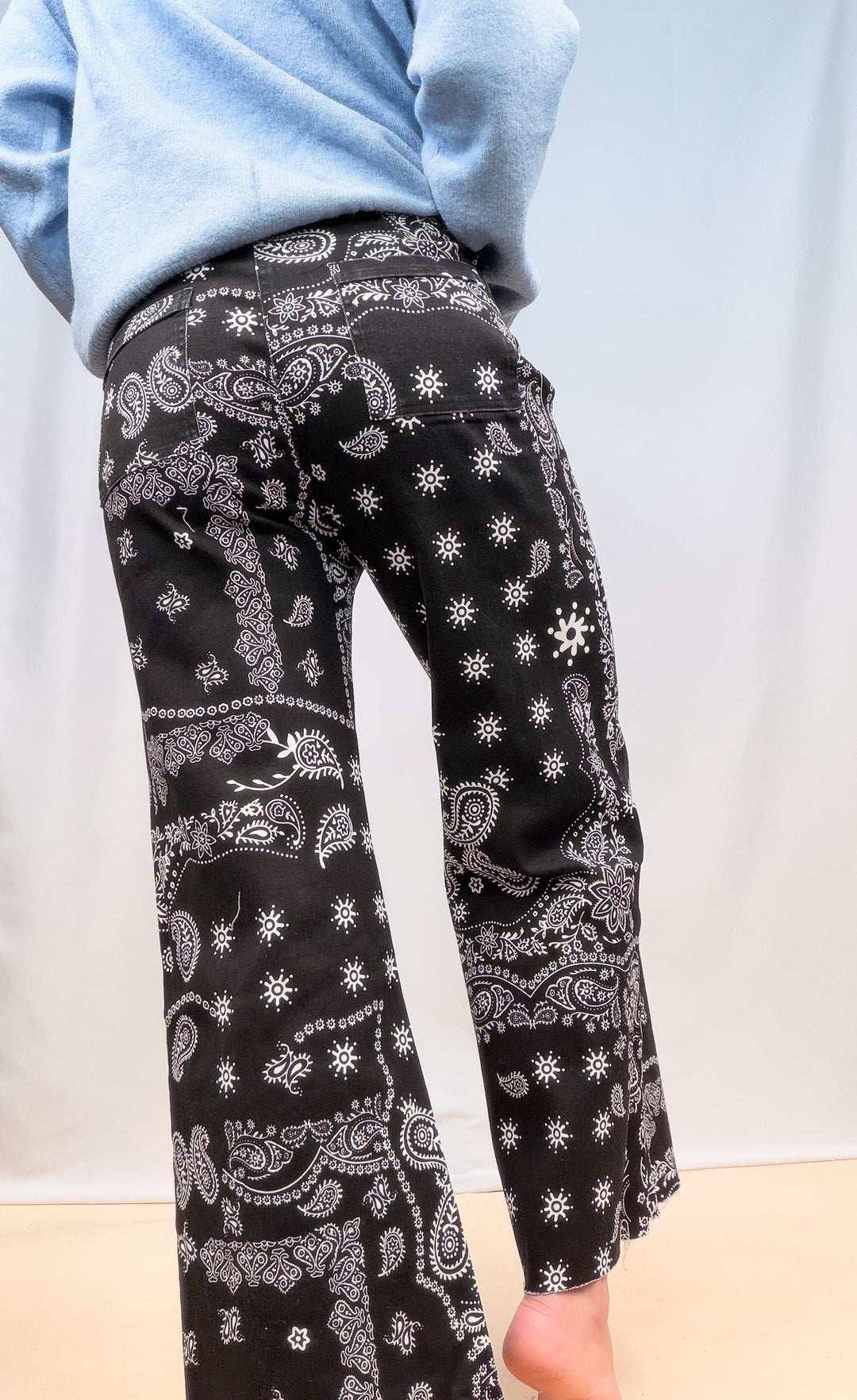 Woman shown from back view waist down wearing black bandana pants on plain background