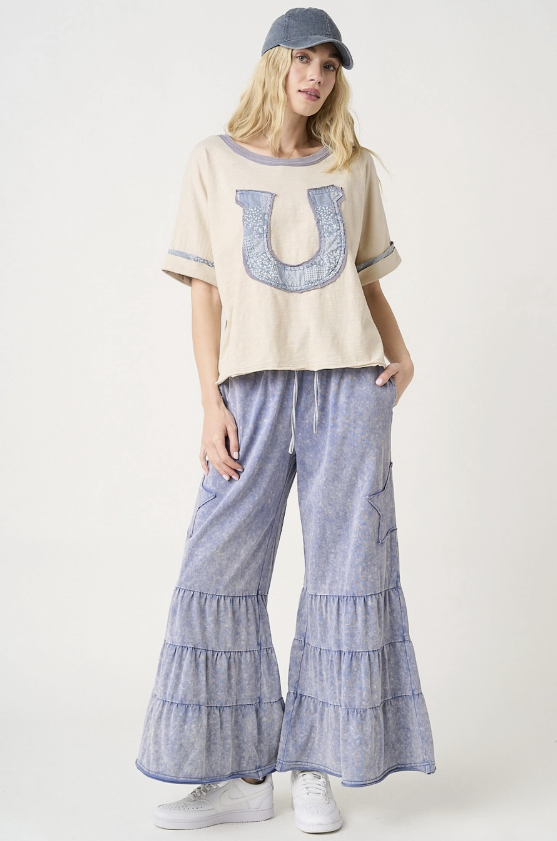Woman wearing a cream top with a large &