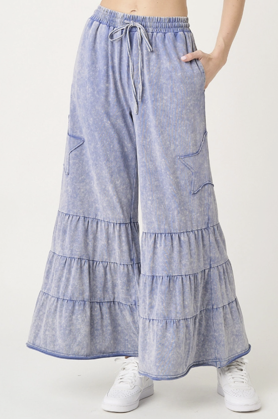 Blue tiered pants worn by a person on a white background