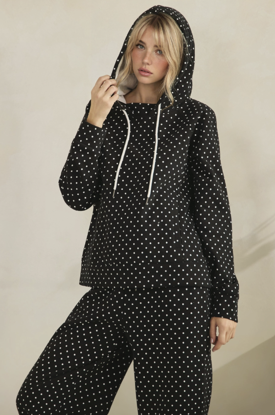 Woman wearing matching black sweat suit with white polka dots on plain background