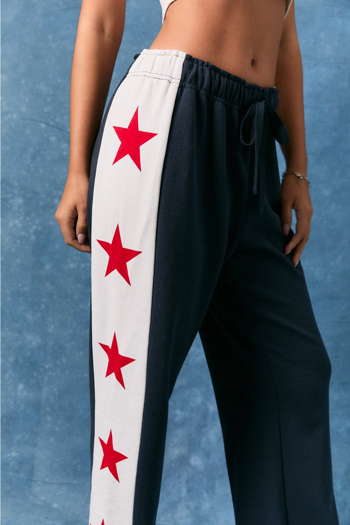 Black pants with red star patterns on a white stripe against a blue background