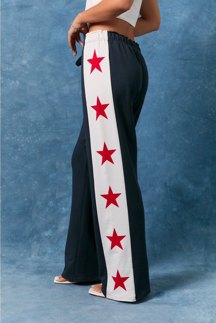 Black pants with red star patterns on a white stripe against a blue background