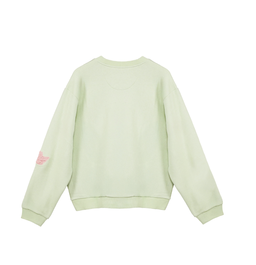 A light sage green crewneck sweatshirt shown from the back, featuring a small pink embroidered wing logo on the left sleeve, set against a plain white background.