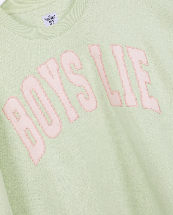A close-up of a pale yellow-green crewneck sweatshirt featuring the words &