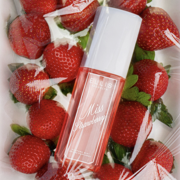 A bottle of EULIS PARIS Miss Strawberry serum surrounded by fresh strawberries on a white background, wrapped in clear plastic.