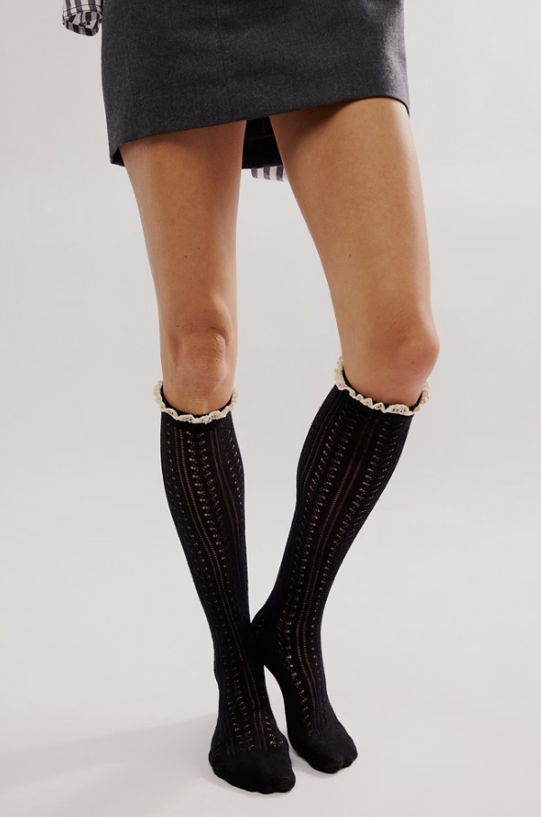 Woman wearing black knee high socks with frill on top with short skirt on white background