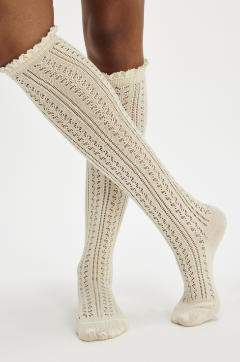 Woman wearing ivory knit knee high socks on white background