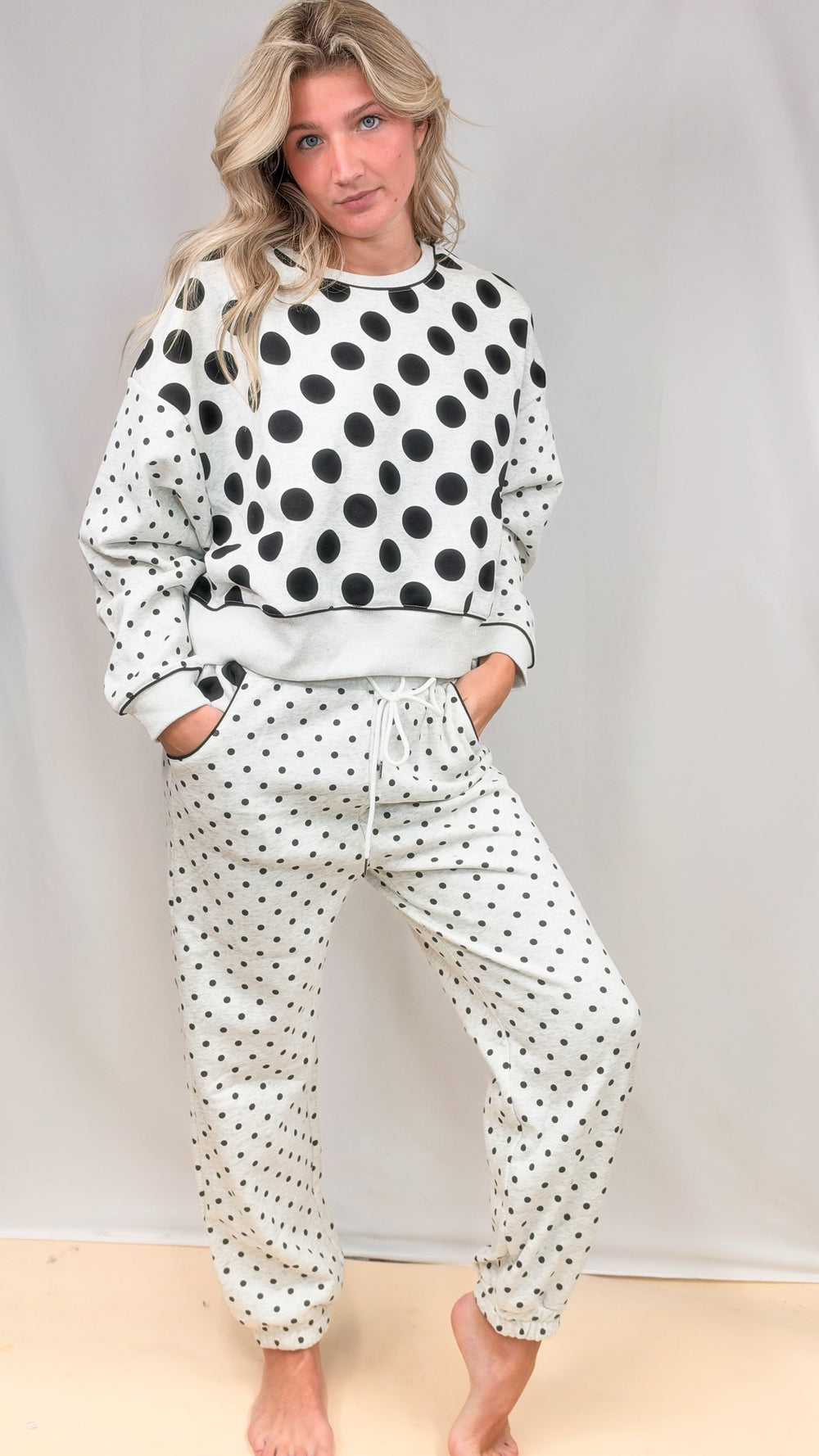 Woman wearing heather grey matching set with black polka dots on top and bottom on plain background