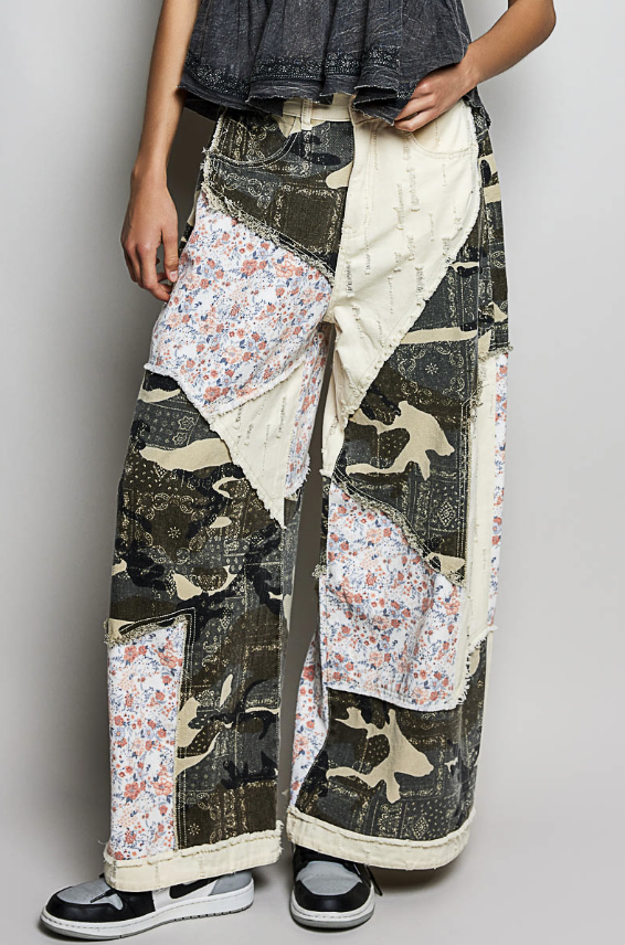 Person wearing a patchwork-style outfit with floral and abstract patterns on a plain background