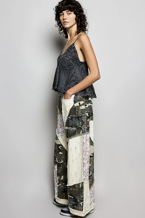 woman wearing patchwork pants with black top on plain background
