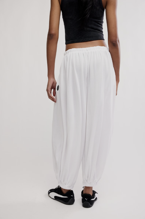 Person wearing a black crop top and white pants on a plain background