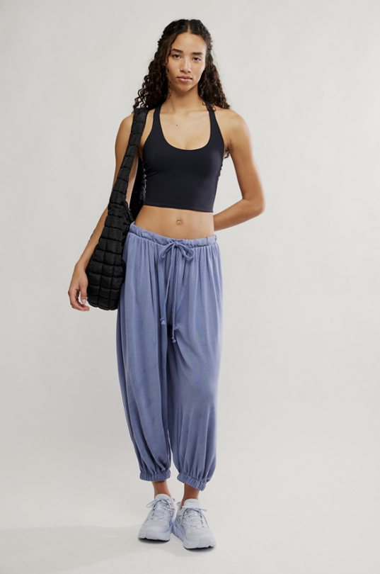 Woman wearing a black sports bra and blue pants, standing against a white background