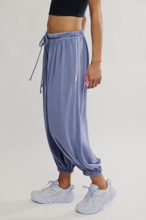 Person wearing blue drawstring pants and white sneakers on a light gray background