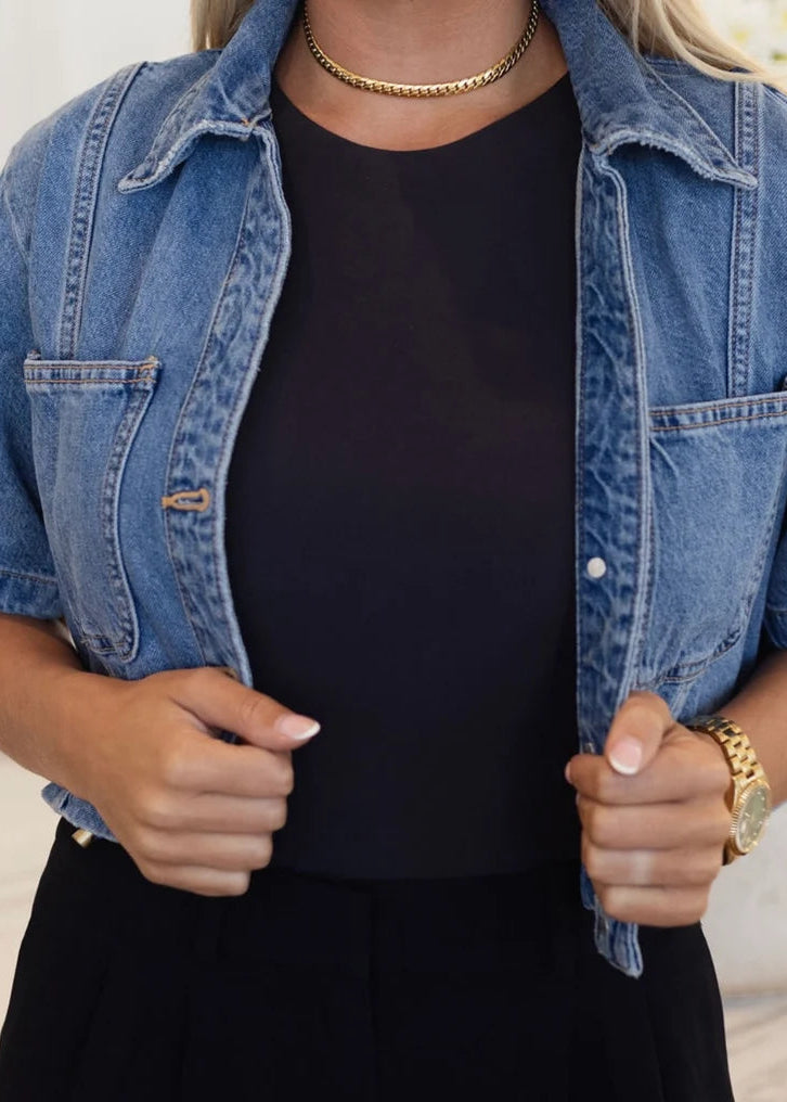 Woman wearing mini curb gold necklace and denim jacket with black dress