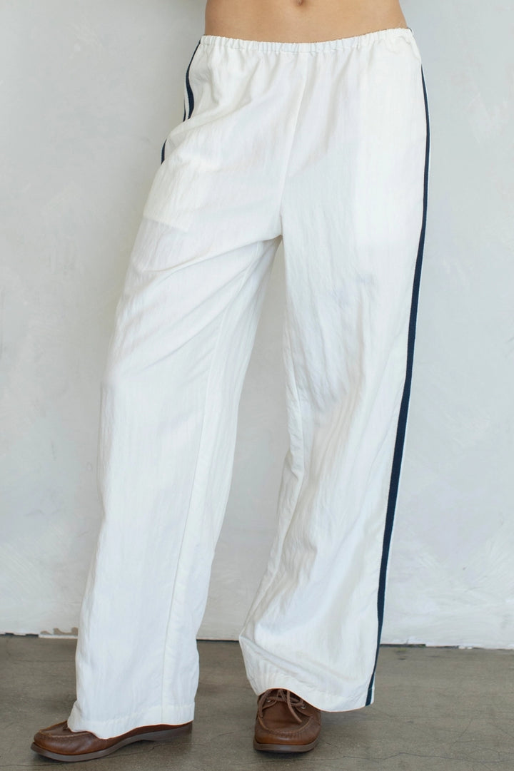 Person wearing ivory pull on pants and loafers on plain background