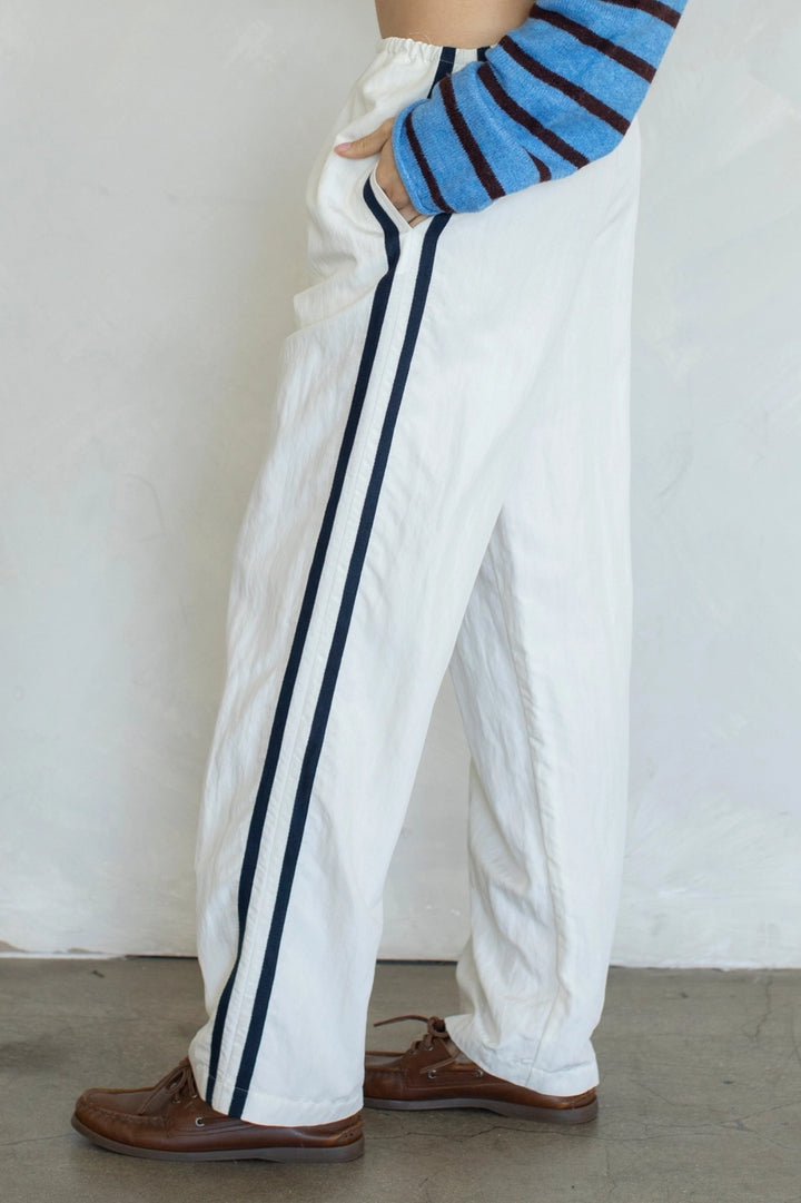 White pants with black stripes worn by a person against a white background