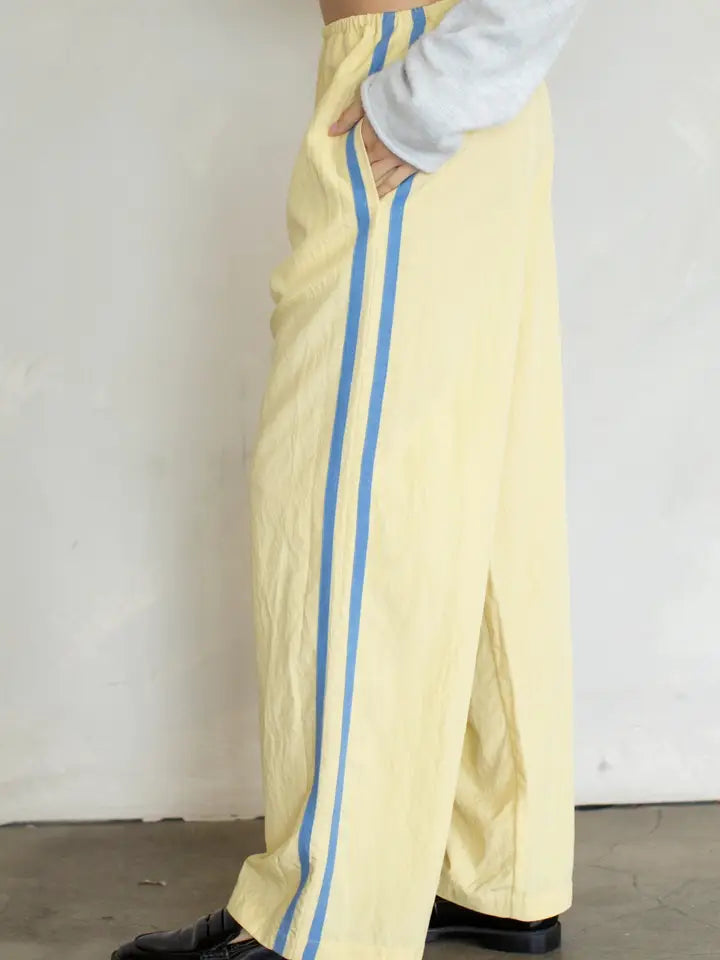 person wearing yellow pant with light blue stripe on plain background