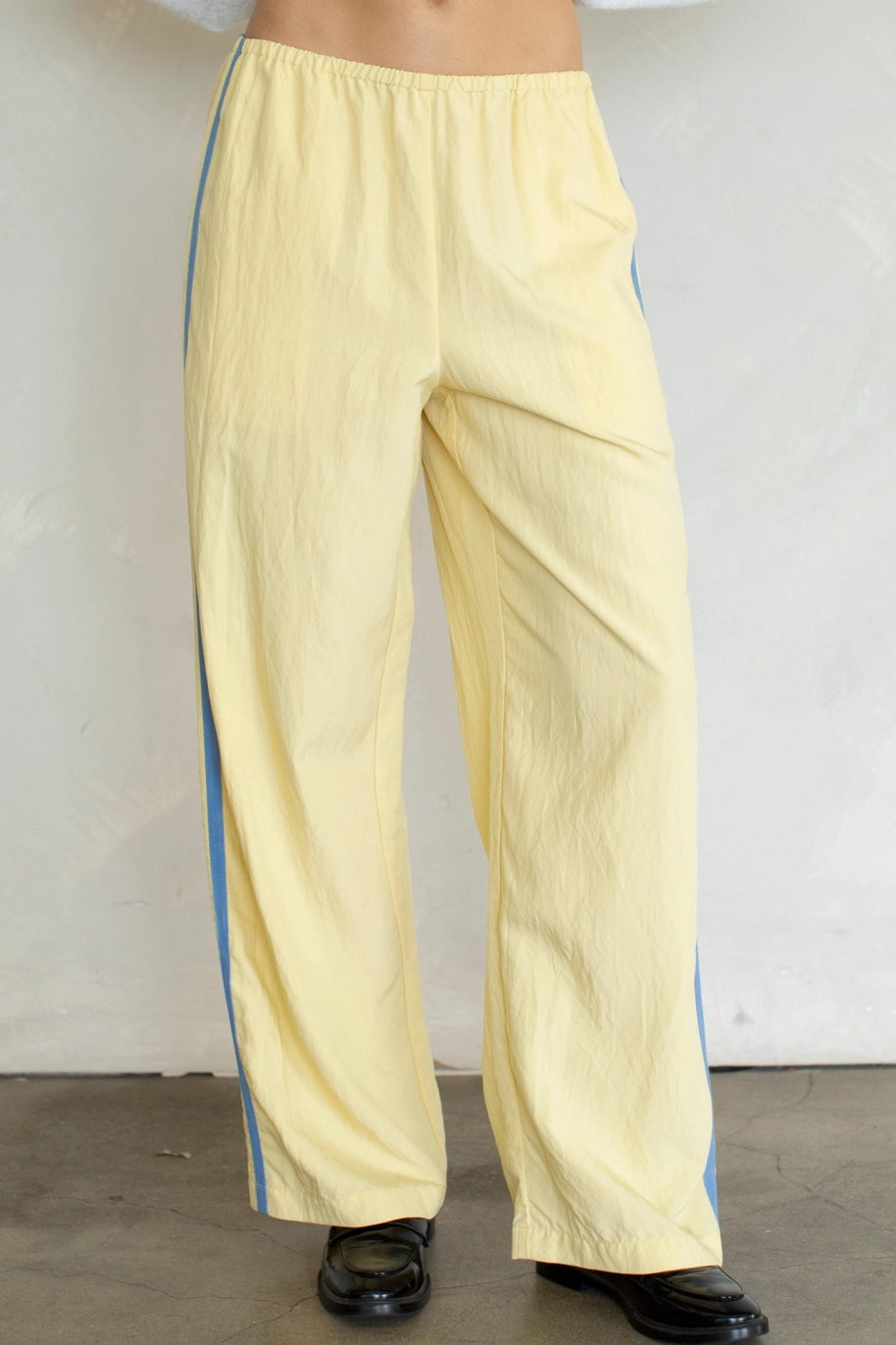 Yellow pants with blue stripes worn by a person against a plain background