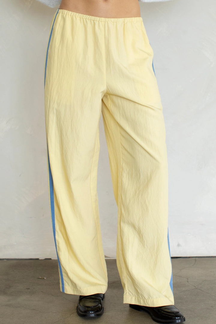 Yellow pants with blue stripes worn by a person against a plain background
