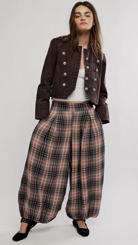 Woman wearing plaid balloon pants with brown jacket on plain background